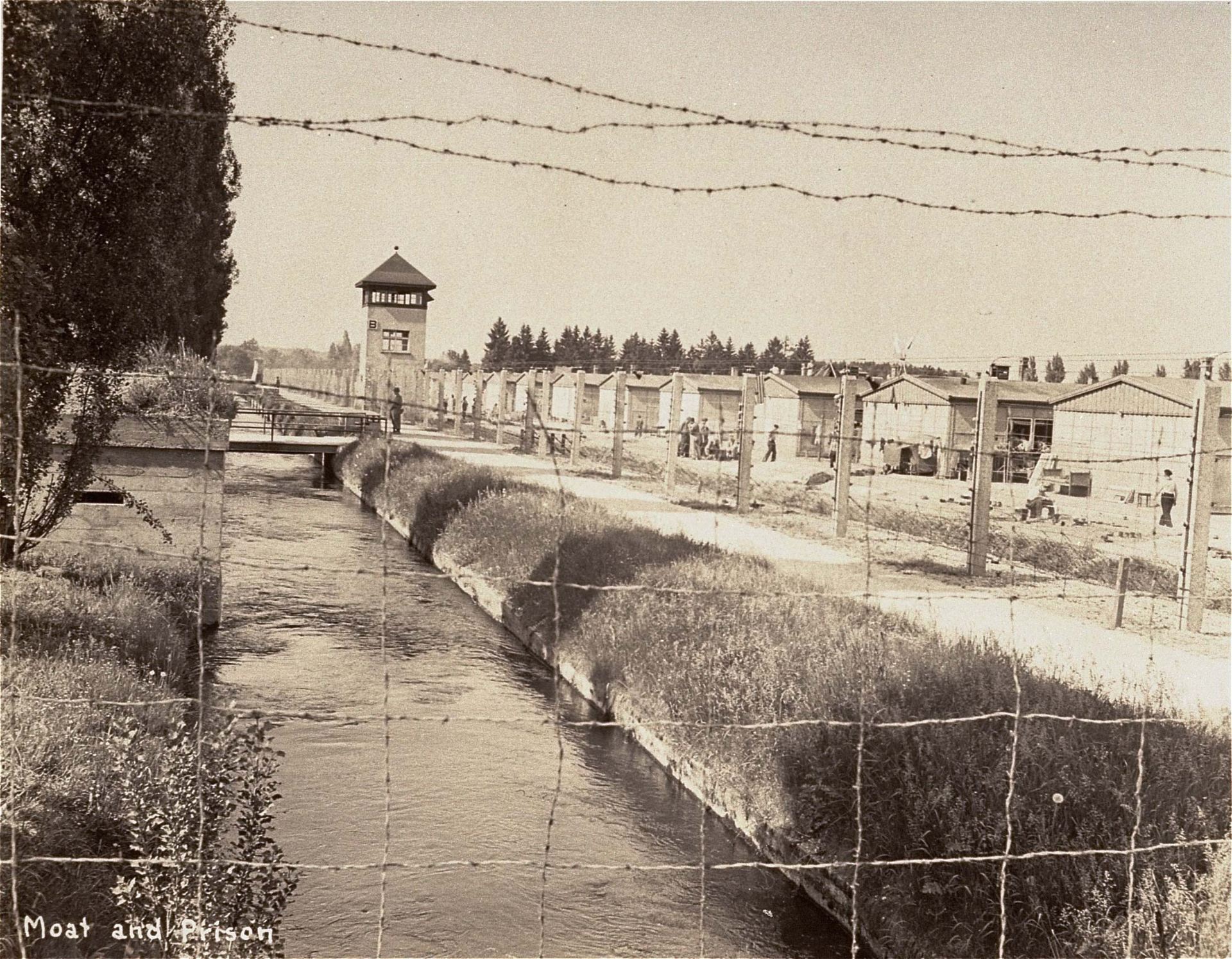 A section of the Dachau concentration camp, including the guard tower, is seen through the barbed wire fence shortly after the camp was liberated by American soldiers on April 29, 1945. (United States Holocaust Memorial Museum, courtesy of Francis Robert Arzt)