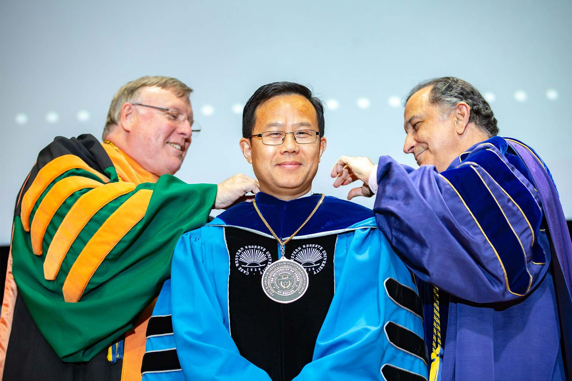 Dr. Baowei Fei, Cecil H. and Ida Green Chair in Systems Biology Science, received his medallion from UT Dallas President Richard C. Benson (left) and Dr. Poras Balsara during the Investiture Ceremony in 2019, the last time the ceremony was held in person at UTD.