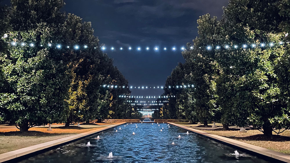 McDermott Mall at night with lights strung above the reflecting pools.